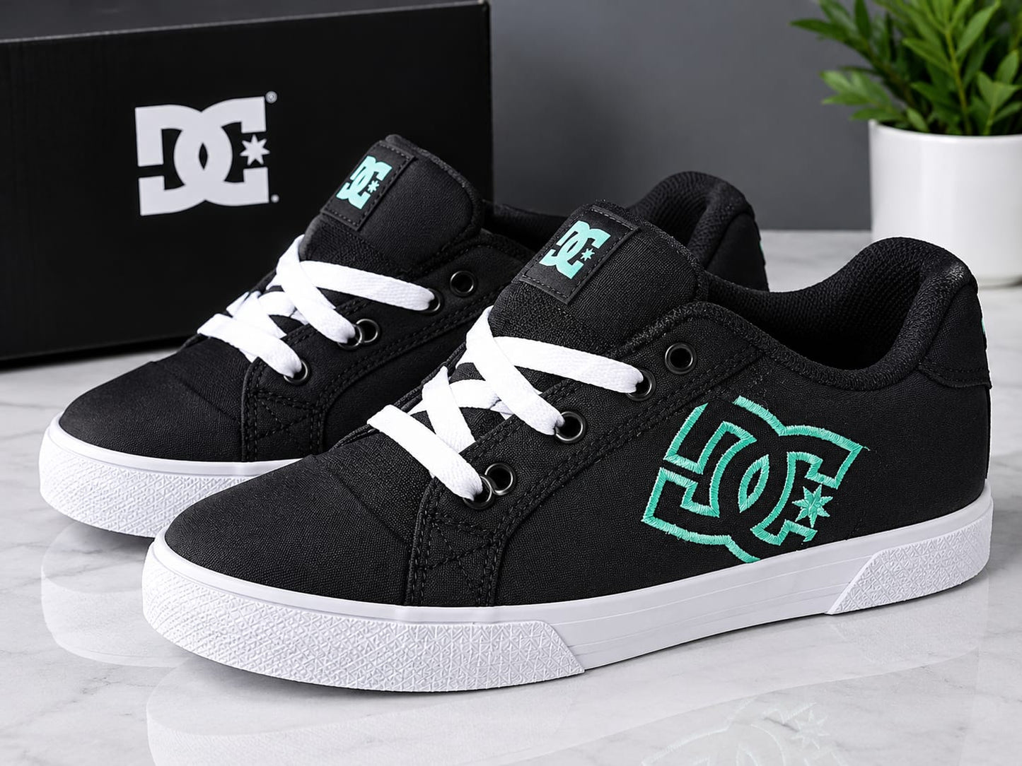 These are the DC Shoes Chelsea skate sneakers in black and aqua, featuring a prominent embroidered teal DC logo on the side